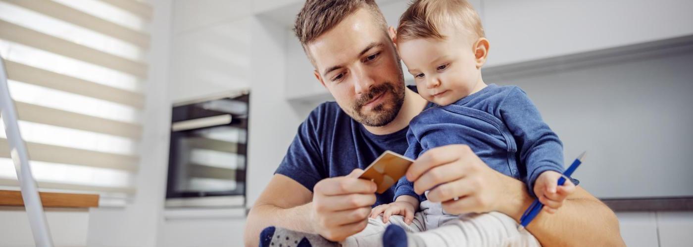 Father and baby looking at credit card to pay bill on computer. 